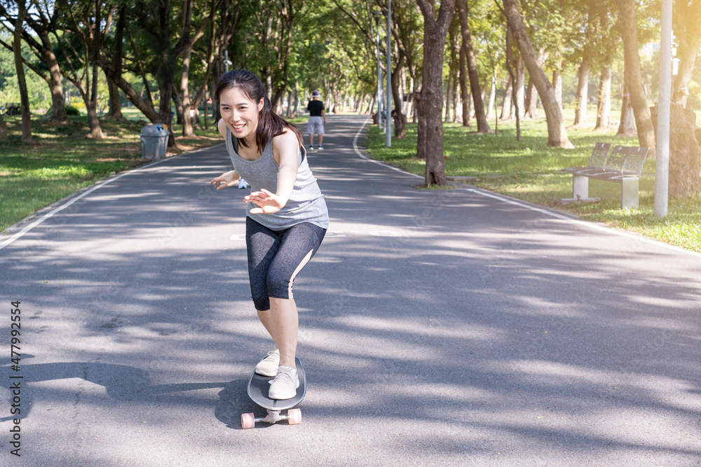 Young teen girl learning to rides a skateboard. Young woman learning skateboarding lesson in the park. Portrait of young female skateboarding in the park. Woman standing and learning to ride skate. Young teen girl learning to rides a skateboard. Young woman learning skateboarding lesson in the park. Portrait of young female skateboarding in the park. Woman standing and learning to ride skate.