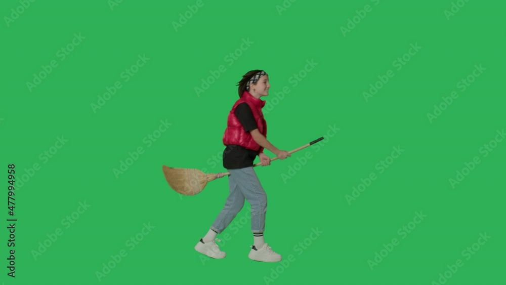 Cute teen girl shows witch flying on broom over green screen. Female kid having fun. Halloween concept. Chroma Key. 4k uhd video footage Cute teen girl shows witch flying on broom over green screen. Female kid having fun. Halloween concept. Chroma Key. 4k uhd video footage