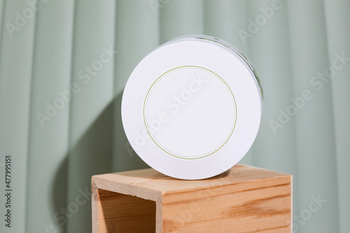 Mockup friendly white plastic cosmetic jar on wooden podium infront of green background