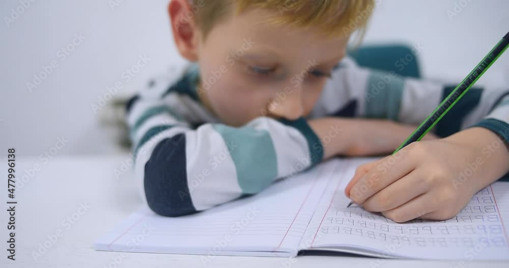 School boy practicing writing the alphabet at home. Boy child kid writing. Homework. School boy practicing writing the alphabet at home. Boy child kid writing. Homework.