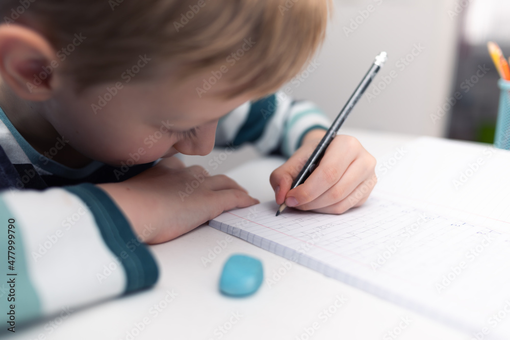 School boy practicing writing the alphabet at home. Boy child kid writing. Homework. School boy practicing writing the alphabet at home. Boy child kid writing. Homework.