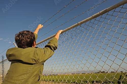 Teenage boy climbing chainlink fence with barbed wire on top, Camarillo, CA, USA photo