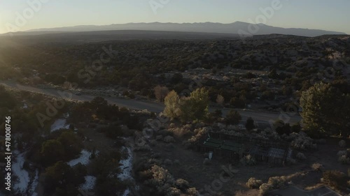 Drone moving right following a remote snowy road at sunrise in the desert