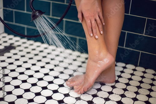 Obraz na płótnie woma foot in the shower cabin is washed by a shower under a jet of water on black and white tile w salonie