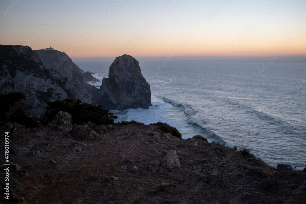 View of the cliffs in the Atlantic Ocean at sunset in Miradouro da Praia do Caneiro, Portugal. View of the cliffs in the Atlantic Ocean at sunset in Miradouro da Praia do Caneiro, Portugal.