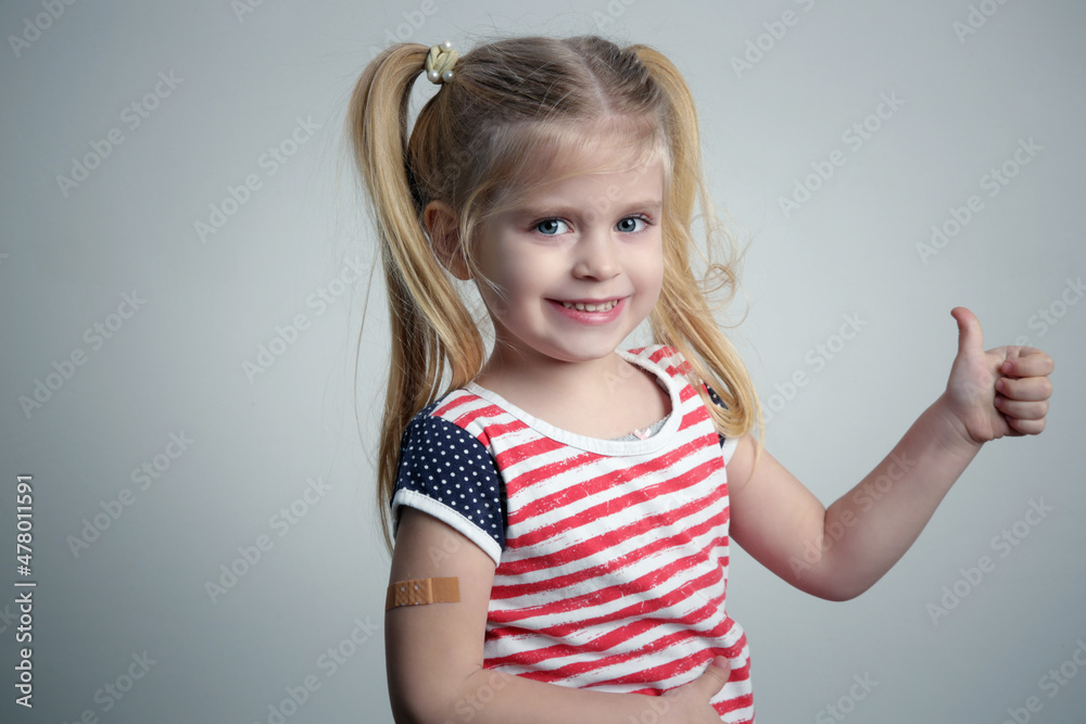 Child vaccination. Little girl showing thumb up gesure and adhezive arm bandage, studio shot. Child vaccination. Little girl showing thumb up gesure and adhezive arm bandage, studio shot.