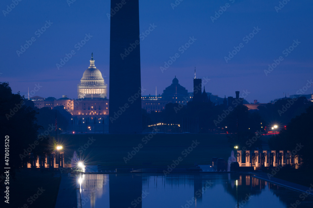 Washington DC monuments including the Capitol and Washington Monument as seen between columns of Lincoln Memorial at night