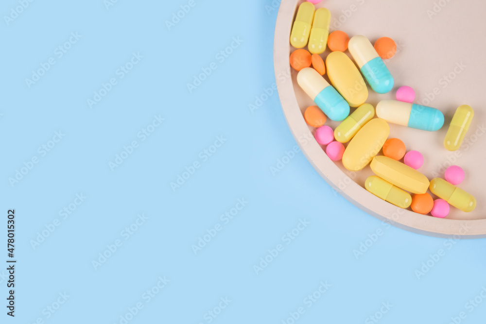 Immune system vitamins and supplemets. Dietary bio supplements. Assorted multicolored medicine pills, capsules and tablets on blue background with copy space for your text. Immune system vitamins and supplemets. Dietary bio supplements. Assorted multicolored medicine pills, capsules and tablets on blue background with copy space for your text.