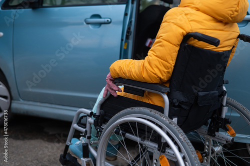 Caucasian woman in a wheelchair gets into the car.  © Михаил Решетников