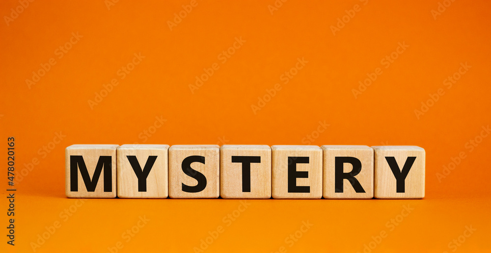 Mystery symbol. The concept word Mystery on wooden cubes. Beautiful orange table, orange background, copy space. Business and mystery mysterious concept.