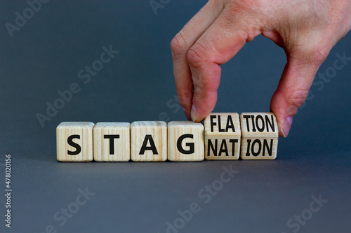 Stagflation or stagnation symbol. Businessman turns cubes, changes the word stagnation to stagflation. Beautiful grey table, grey background, copy space. Business, stagflation or stagnation concept.