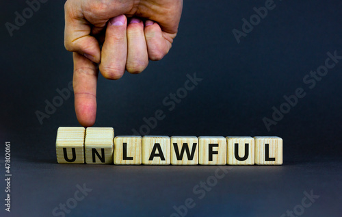 Lawful or unlawful symbol. Businessman turns wooden cubes and changes the word unlawful to lawful. Beautiful grey table, grey background, copy space. Business and lawful or unlawful concept.