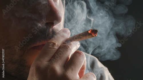 Man smoking a marijuana weed joint, inhaling cannabis smoke. photo