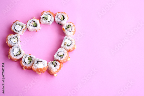 Sushi set in the shape of a heart on pink background. Valentine day or March 8th food concept.The concept of a romantic dinner at a sushi bar for February 14th. 