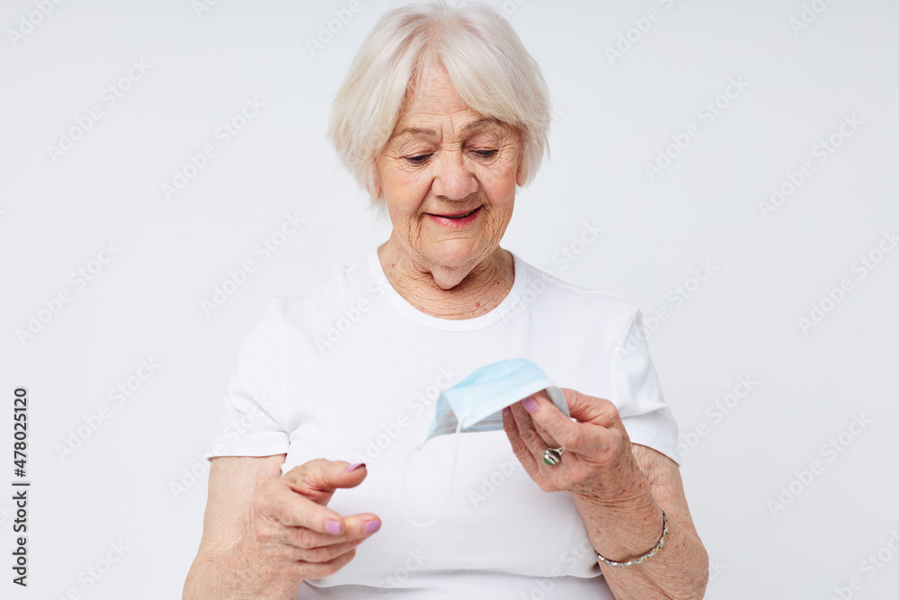 Portrait of an old friendly woman in casual t-shirt and medical mask isolated background Portrait of an old friendly woman in casual t-shirt and medical mask isolated background