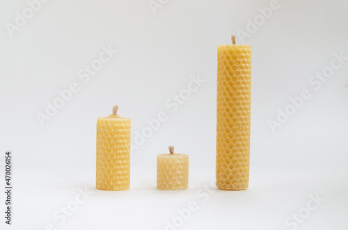 Yellow round wax candles with a honeycomb pattern on a white background