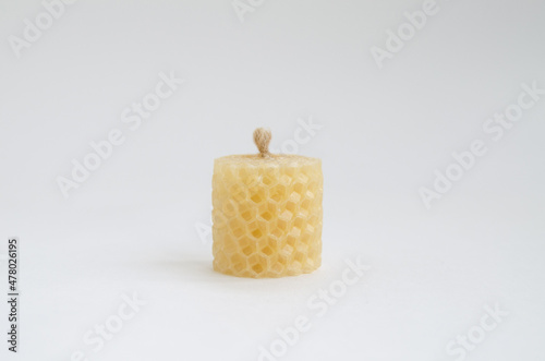 Yellow round wax candles with a honeycomb pattern on a white background