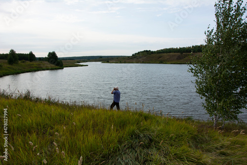 Lake shore with trees and tall grass, a photographer in the Russian expanses, August evening in Russia.