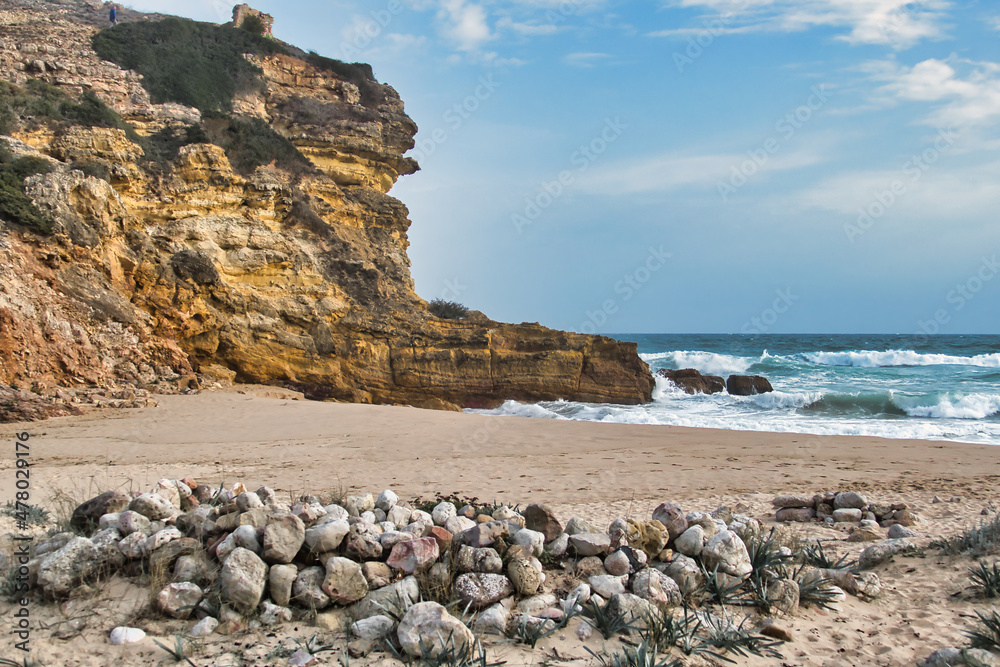 Beach with stones, limestone cliffs, waves and blue sea of Praia do Figueira, between Sagres and Lagos, Algarve, Portugal
