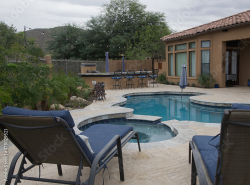 Blue lounge chairs on a travertine Tile pool deck.