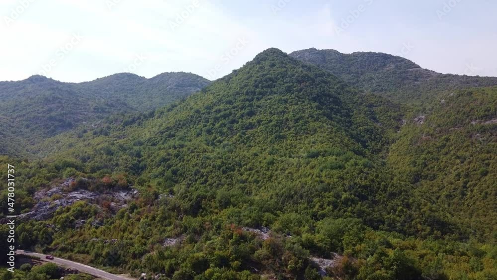 A small building in the middle of the mountain. Narrow mountain road passing near it. Aerial View of National Park Skadar Lake in Montenegro. A small building in the middle of the mountain. Narrow mountain road passing near it. Aerial View of National Park Skadar Lake in Montenegro.