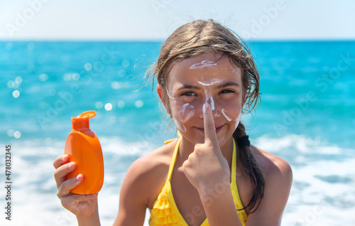 Принти на полотні The child is putting sunscreen on her face. Selective focus.