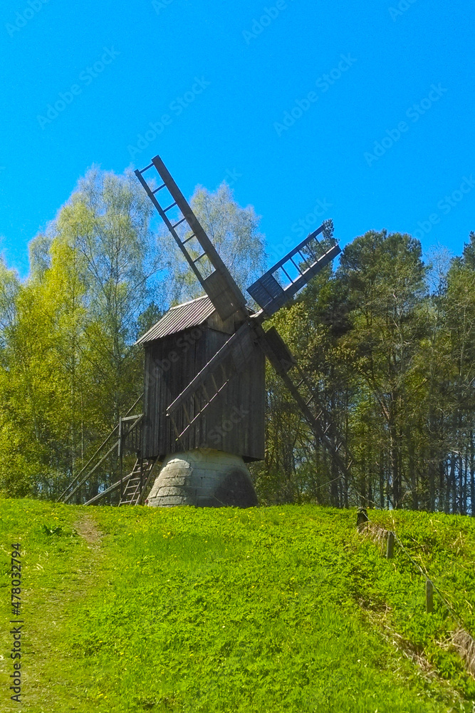 An old wooden mill against the backdrop of a green forest. An old wooden mill against the backdrop of a green forest.