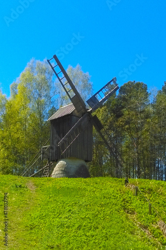 An old wooden mill against the backdrop of a green forest.