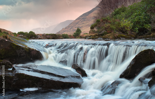 Beautiful sunrise nature scenery of small waterfall on river Erriff with mountains in the background at Aesleagh in county Mayo  Ireland 