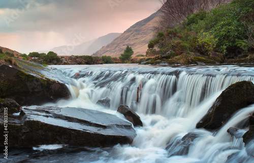Beautiful sunrise nature scenery of small waterfall on river Erriff with mountains in the background at Aesleagh in county Mayo, Ireland  photo