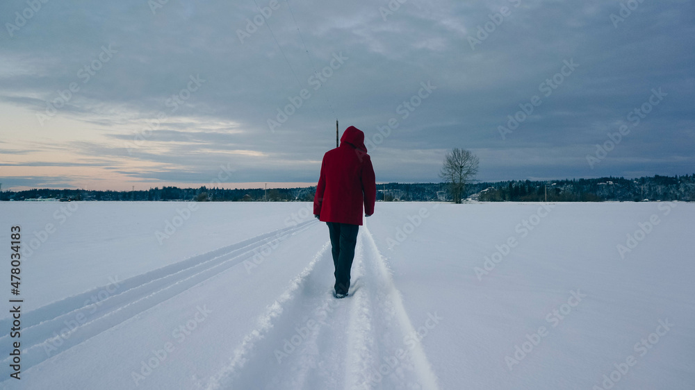 Woman in red jacket walking away down a snowy road