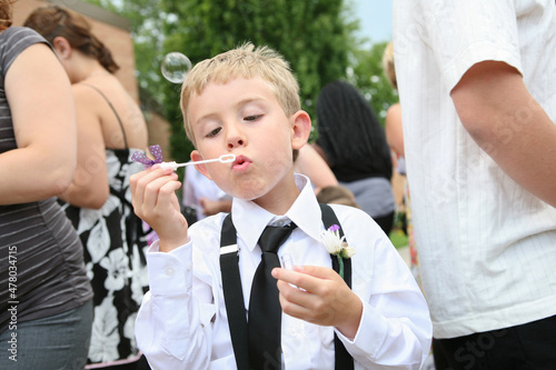 Young boy at a wedding blowing bubbles with a bubble wand waiting for bride and groom photo