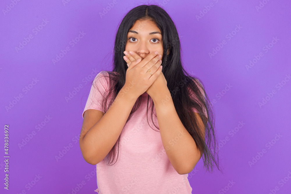 Hispanic brunette girl wearing pink t-shirt over purple background shocked covering mouth with hands for mistake. Secret concept. Hispanic brunette girl wearing pink t-shirt over purple background shocked covering mouth with hands for mistake. Secret concept.