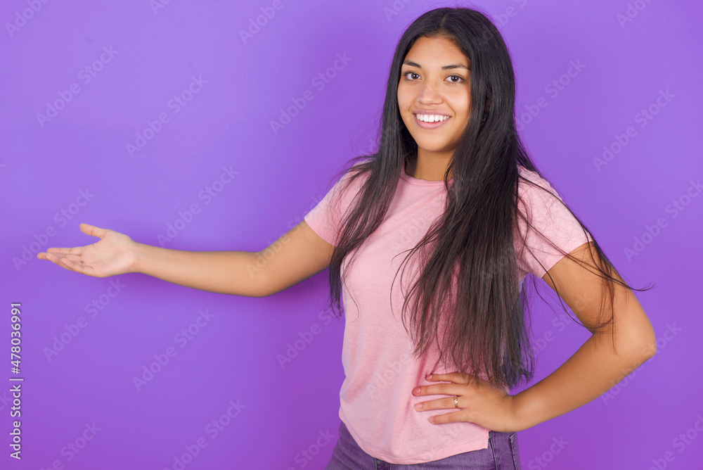 Hispanic brunette girl wearing pink t-shirt over purple background feeling happy and cheerful, smiling and welcoming you, inviting you in with a friendly gesture Hispanic brunette girl wearing pink t-shirt over purple background feeling happy and cheerful, smiling and welcoming you, inviting you in with a friendly gesture