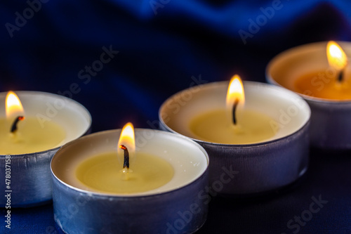 Round candles are burning on a blue background. Tea light set. The symbol of romance.