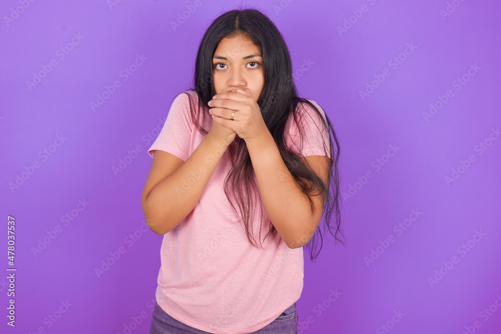 Hispanic brunette girl wearing pink t-shirt over purple background holding oneself, feels very cold outside, hopes that will not get cold Hispanic brunette girl wearing pink t-shirt over purple background holding oneself, feels very cold outside, hopes that will not get cold