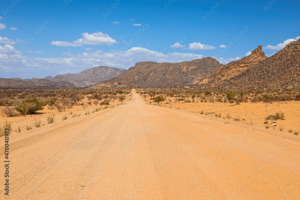 Empty red dirt road through the desert mountains of Namibia