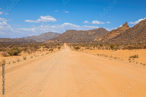 Empty red dirt road through the desert mountains of Namibia
