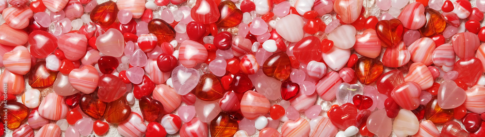 Background of white, pink and red glass beads in the shape of a heart for a banner and other designs for Valentine's Day and other holidays, selective focus, horizontal orientation. Background of white, pink and red glass beads in the shape of a heart for a banner and other designs for Valentine's Day and other holidays, selective focus, horizontal orientation.