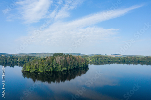 The island and its green vegetation in the Lac des Settons in Europe, France, Burgundy, Nievre, Morvan, in summer, on a sunny day. photo