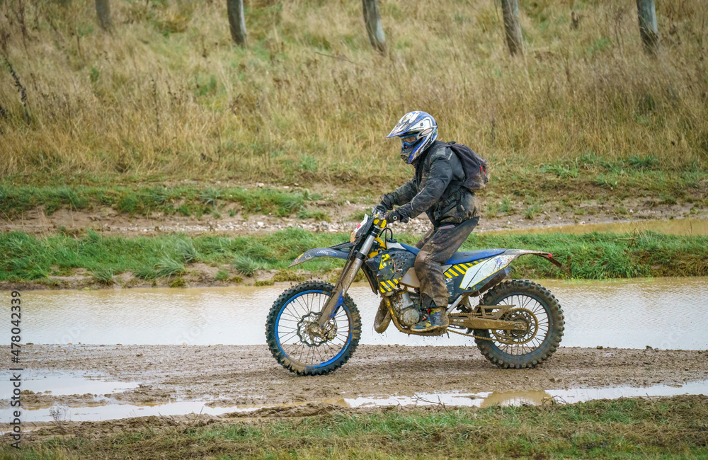 Obraz premium motorcyclist ridiing his motorbike across a water-logged muddy track 
