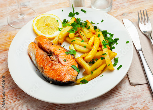 Tasty grilled salmon fillet with french fries and slice of lemon