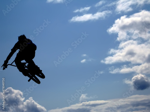 BMX rider performing air trick clouds as background