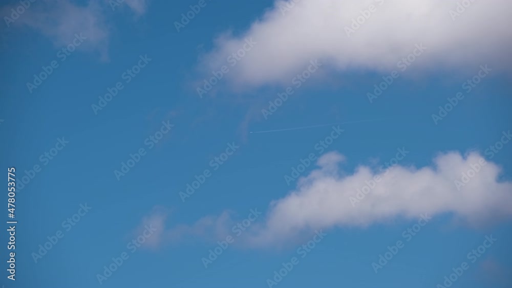 Distant passenger jet plane flying on high altitude on blue sky with white clouds leaving smoke trace of contrail behind. Air traveling concept Distant passenger jet plane flying on high altitude on blue sky with white clouds leaving smoke trace of contrail behind. Air traveling concept