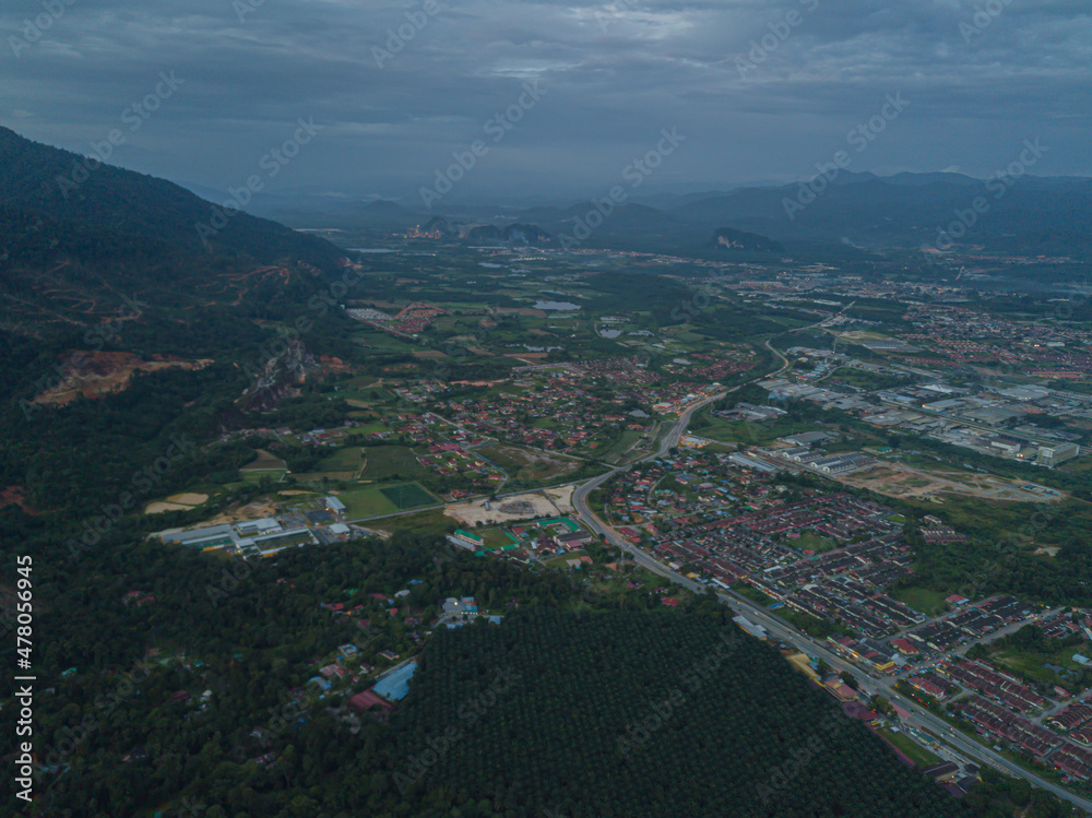 Obraz premium Drone shot of residential area near green mountains range at Chemor, Ipoh, Perak, Malaysia.