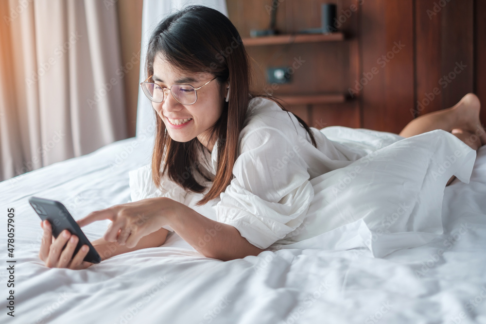 woman using smartphone for social media, young female watching movies by mobile phone on bed at home. technology, network, online shopping, e commerce, lifestyle and digital communication concept woman using smartphone for social media, young female watching movies by mobile phone on bed at home. technology, network, online shopping, e commerce, lifestyle and digital communication concept