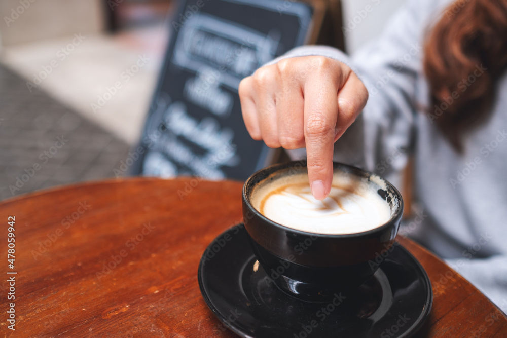 Closeup of a woman pointing at a hot coffee
