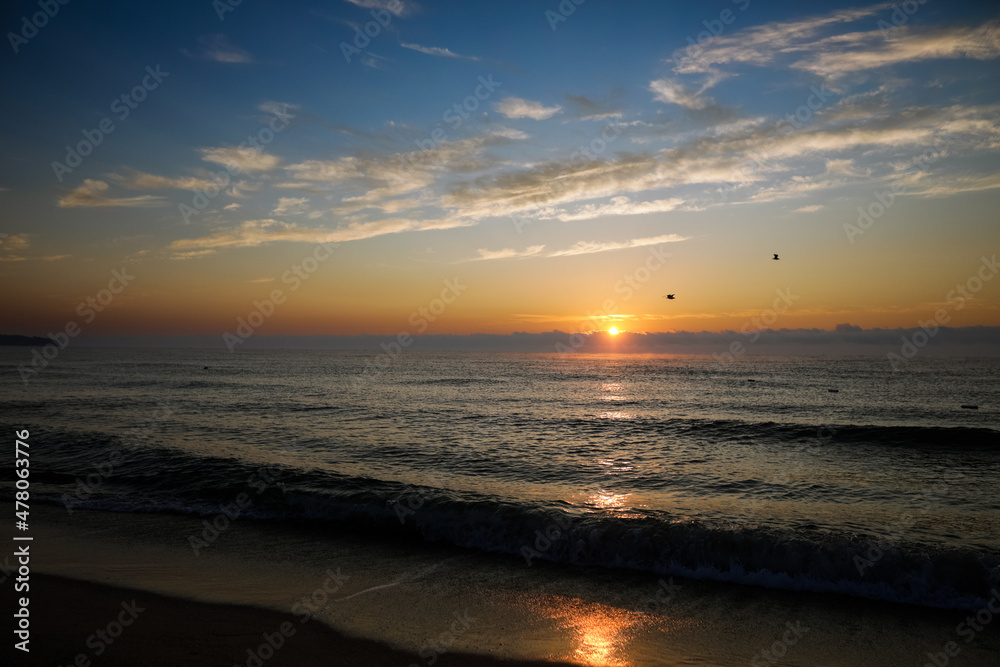 Gentle waves while the sun is rising over the Black Sea in the Obzor resort in Bulgaria on a calm and warm summer day.