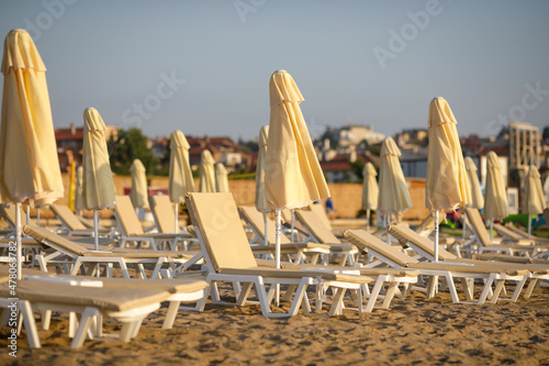 Lounge chairs and sun umbrellas on the beach on a calm and warm summer morning at the Black Sea in the Obzor resort in Bulgaria. photo