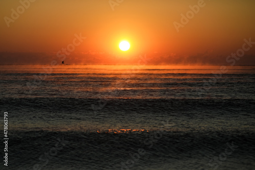 Gentle waves while the sun is rising over the Black Sea in the Obzor resort in Bulgaria on a calm and warm summer day.